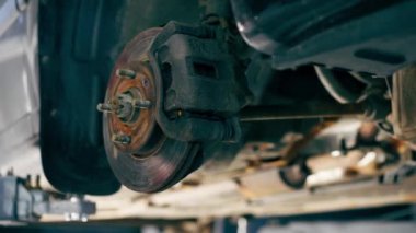 Bir otomobil tamircisi için özel bir mekanizma tarafından bir benzin istasyonunda tekersiz siyah bir arabanın yakın plan çekimi.