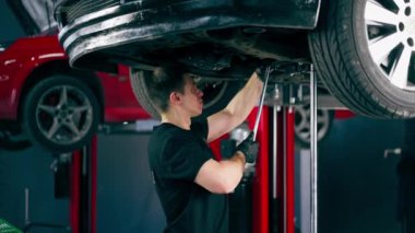 Bir benzin istasyonundaki oto tamirciyi kapat asansörde kaldırılan bir arabayı kontrol et, mekanik bir araçla arızaları düzelt motor alt gövdenin parçasını