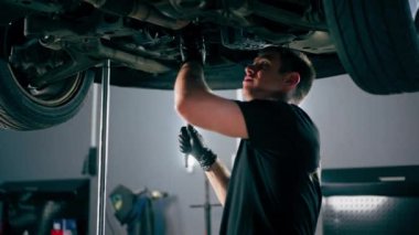 Bir benzin istasyonundaki oto tamirciyi kapat asansörde kaldırılan bir arabayı kontrol et, mekanik bir araçla arızaları düzelt motor alt gövdenin parçasını