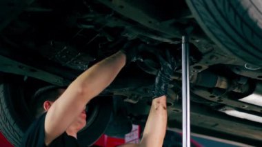 Bir benzin istasyonundaki oto tamirciyi kapat asansörde kaldırılan bir arabayı kontrol et, mekanik bir araçla arızaları düzelt motor alt gövdenin parçasını