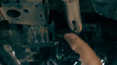 bir benzin istasyonunda bir oto tamirciyi kapatan dikey video asansörde kaldırılan bir arabayı kontrol eder, mekanik bir araçla arıza düzeltir motor alt gövdenin bir parçasıdır