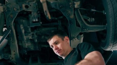 Bir benzin istasyonundaki oto tamirciyi kapat asansörde kaldırılan bir arabayı kontrol et, mekanik bir araçla arızaları düzelt motor alt gövdenin parçasını