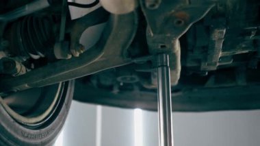 Bir benzin istasyonundaki oto tamirciyi kapat asansörde kaldırılan bir arabayı kontrol et, mekanik bir araçla arızaları düzelt motor alt gövdenin parçasını