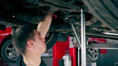 Bir benzin istasyonundaki oto tamirciyi kapat asansörde kaldırılan bir arabayı kontrol et, mekanik bir araçla arızaları düzelt motor alt gövdenin parçasını