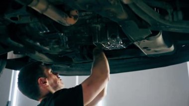 Bir benzin istasyonundaki oto tamirciyi kapat asansörde kaldırılan bir arabayı kontrol et, mekanik bir araçla arızaları düzelt motor alt gövdenin parçasını