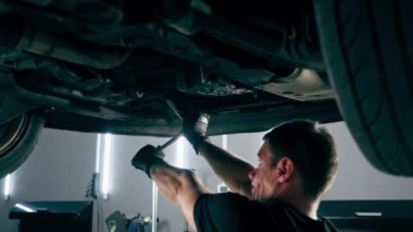 Bir benzin istasyonundaki oto tamirciyi kapat asansörde kaldırılan bir arabayı kontrol et, mekanik bir araçla arızaları düzelt motor alt gövdenin parçasını