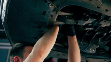 Bir benzin istasyonundaki oto tamirciyi kapat asansörde kaldırılan bir arabayı kontrol et, mekanik bir araçla arızaları düzelt motor alt gövdenin parçasını