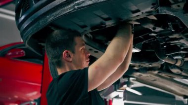 Bir benzin istasyonundaki oto tamirciyi kapat asansörde kaldırılan bir arabayı kontrol et, mekanik bir araçla arızaları düzelt motor alt gövdenin parçasını