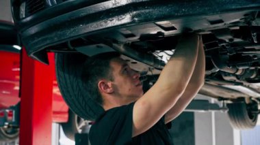 Bir benzin istasyonundaki oto tamirciyi kapat asansörde kaldırılan bir arabayı kontrol et, mekanik bir araçla arızaları düzelt motor alt gövdenin parçasını