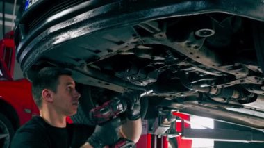 Bir benzin istasyonundaki oto tamirciyi kapat asansörde kaldırılan bir arabayı kontrol et, mekanik bir araçla arızaları düzelt motor alt gövdenin parçasını