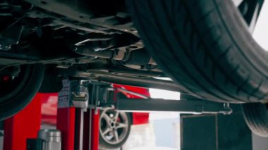 Bir otomobil tamircisi için özel bir mekanizma tarafından bir benzin istasyonunda tekerlekleri yükseltilmiş bir arabanın yakın çekimi.