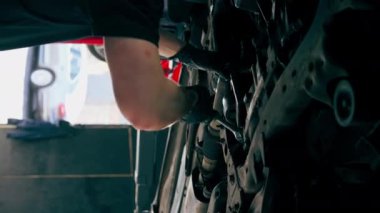 dikey video bir otomobil tamircisi asansörde kaldırılan bir arabayı kontrol eder, mekanik bir araçla arızaları düzeltir motor alt gövdenin bir parçasıdır