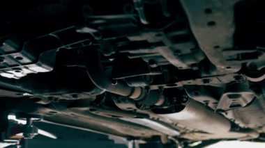 Bir araba servisinde asansörle yakın plan. Tekerlekle ilgili bir sorunu tamir etmek için bir makine. Paslı yayı olan bir tekerlek.