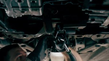 Bir benzin istasyonundaki oto tamirciyi kapat asansörde kaldırılan bir arabayı kontrol et, mekanik bir araçla arızaları düzelt motor alt gövdenin parçasını