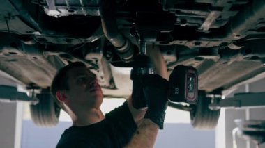 Bir benzin istasyonundaki oto tamirciyi kapat asansörde kaldırılan bir arabayı kontrol et, mekanik bir araçla arızaları düzelt motor alt gövdenin parçasını