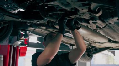 Bir benzin istasyonundaki oto tamirciyi kapat asansörde kaldırılan bir arabayı kontrol et, mekanik bir araçla arızaları düzelt motor alt gövdenin parçasını