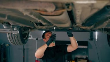 Bir benzin istasyonundaki oto tamirciyi kapat asansörde kaldırılan bir arabayı kontrol et, mekanik bir araçla arızaları düzelt motor alt gövdenin parçasını