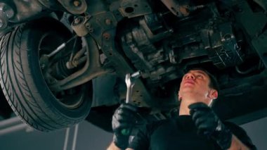 Bir benzin istasyonundaki oto tamirciyi kapat asansörde kaldırılan bir arabayı kontrol et, mekanik bir araçla arızaları düzelt motor alt gövdenin parçasını