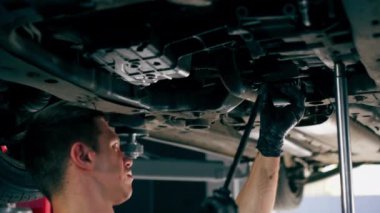 Bir benzin istasyonundaki oto tamirciyi kapat asansörde kaldırılan bir arabayı kontrol et, mekanik bir araçla arızaları düzelt motor alt gövdenin parçasını