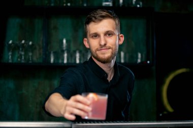 Bartender holding a glass filled with fresh rose cocktail with sour and sweet taste clipart