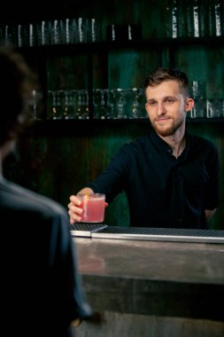 Bartender holding a glass filled with fresh rose cocktail with sour and sweet taste give it client clipart