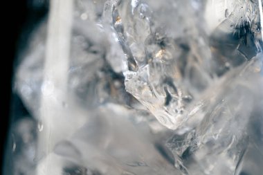 Siyah bir zemin üzerinde şarap kadehinin makro çerçevesi. Kabaca ezilmiş buzlu, bardakta susuz, soğuk, alkollü bir içecek.