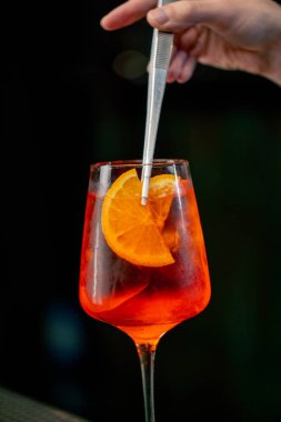 Siyah arka planda bir şarap kadehinin yakın plan görüntüsü. Cam camda, portakal rengi Aperol Spritz ile ezilmiş buz var. Camda tam yoğunlaşma.