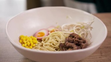 Bir fast food işletmesine yakın bir yerde siyah üniformalı büyük bir şef Japon udon çorbasını hazırlıyor.