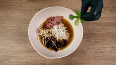 Bir fast food işletmesinde siyah üniformalı büyük bir şef Japon udon çorbasını hazırlar ve çorba döker.