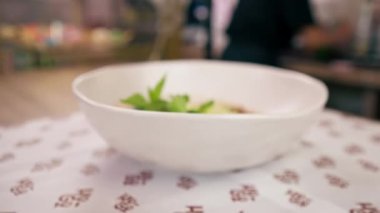 Bir fast food işletmesine yakın bir yerde siyah üniformalı büyük bir şef Japon udon çorbasını hazırlıyor.