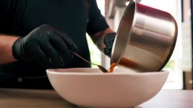 Bir fast food işletmesinde dikey video kapanıyor siyah üniformalı büyük bir aşçı ahşap bir masa kaşığının üzerinde sos olarak pirinç tabağına konuyor.