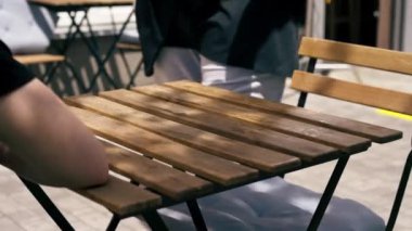 Caddedeki bir restoranda, ahşap bir masanın üzerinde, şef masaya sıcak bir salata, güneşte kızarmış tavuk ve domatesle birlikte mavi bir tabak koyar.