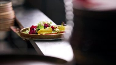 Profesyonel bir mutfakta, temiz metal bir masada, ahşap bir tabakta, domatesli ve mozzarella tostlu güzel bir salata.