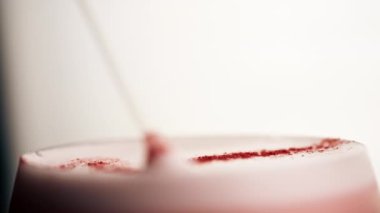 Arka planda pembe köpüklü bir şarap kadehinin makro çerçevesi. Bardakta köpüklü, susuz, alkollü, turuncu bir içecek.