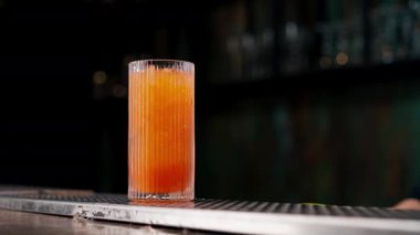 Güzel kristal bardak ve pembe alkollü içecek. Adamın biri cımbızla süslüyor. İki siyah cımbız.