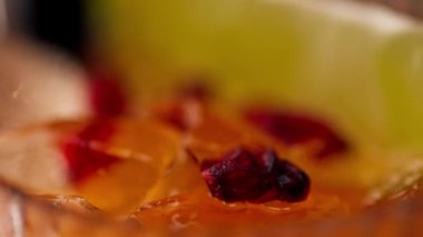 Siyah bir zemin üzerinde şarap kadehinin makro çerçevesi. Bardakta ezilmiş buz, soğuk turuncu alkollü içecek.