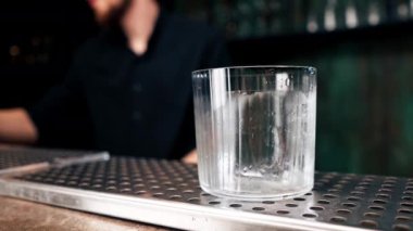 Buz küplerini bardakla kaplayın. Tahta tezgahta alkolle. Arka planda karanlık, detaylarla dolu.