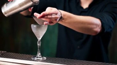 Erkek barmen barmene yaklaşın. Çelik bardaktan bardaktaki eleğe kadar alkollü bir içecek doldurun.