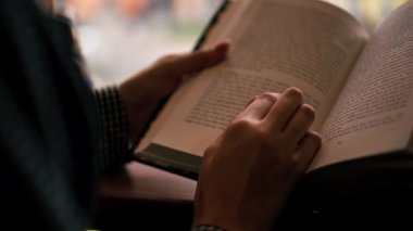 Pencerenin yakınındaki bir kitapçıda el ele tutuşan güzel bir öğrenci oturuyor ve sınavlara hazırlanıyor.