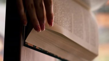 Pencerenin yakınındaki bir kitapçıda el ele tutuşan güzel bir öğrenci oturmuş kitap okuyor sınavlara hazırlanıyor.