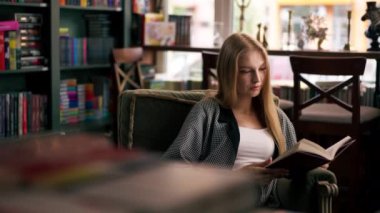 Güzel bir kitapçıda, uzun saçlı genç bir kız kitap akşamları boş zamanlarını kitap okuyarak geçiriyor.