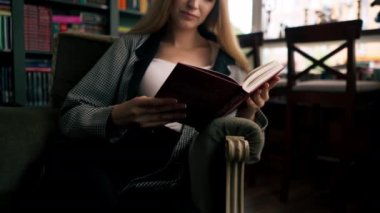Güzel bir kitapçıda yakın plan çekimler, uzun saçlı genç bir kız boş zamanlarında kitap okuyor.