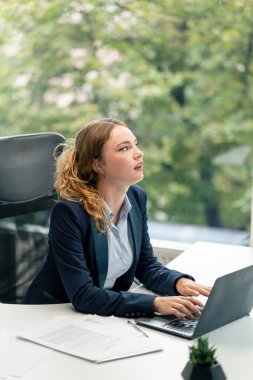 Geniş pencereli modern bir ofiste mavi gömlekli güzel bir işçi kameraya bakar genç bir patron.