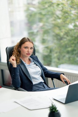 Modern bir ofiste, geniş pencereli kameraya bakın. Mavi gömlekli, dizüstü bilgisayarlı güzel bir işçi kameraya bakar. Genç bir patron.