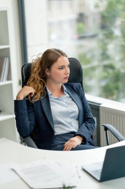 Modern bir ofiste geniş pencereli mavi gömlekli güzel bir işçi kameraya bakar düşünceli genç bir patron.