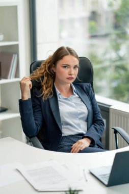 Modern bir ofiste, geniş pencereli kameraya bakın. Mavi gömlekli, dizüstü bilgisayarlı güzel bir işçi kameraya bakar. Genç bir patron.