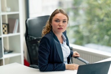 Modern bir ofiste, geniş pencereli kameraya bakın. Mavi gömlekli, dizüstü bilgisayarlı güzel bir işçi kameraya bakar. Genç bir patron.