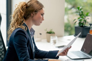 Modern bir ofiste geniş pencereli mavi gömlekli güzel bir işçi laptoplu genç bir patron belgelerle çalışıyor.