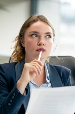 Modern bir ofise yakın büyük bir penceresi olan mavi gömlekli güzel bir işçi dizüstü bilgisayarlı genç bir patron belgelerle çalışan genç bir patron.