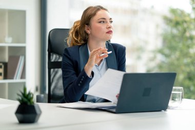 Modern bir ofiste geniş pencereli mavi gömlekli güzel bir işçi laptoplu genç bir patron belgelerle çalışıyor.
